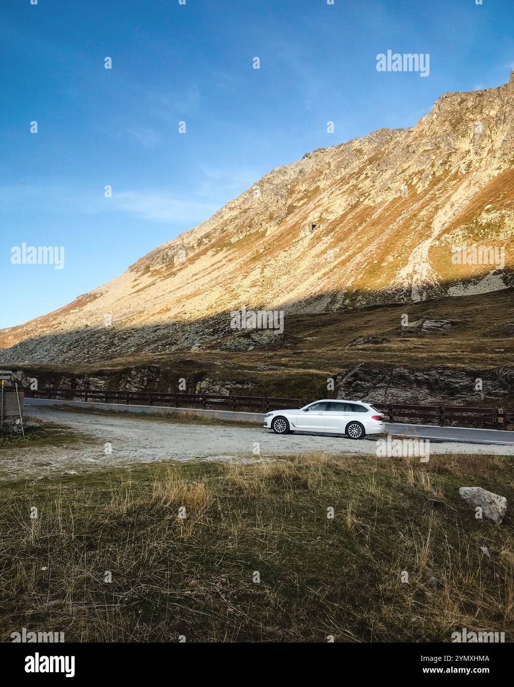 Weißer BMW-Wagen in den Lepontinischen Alpen. Seitenansicht des 5er BMW bei Sonnenuntergang. Stockfoto