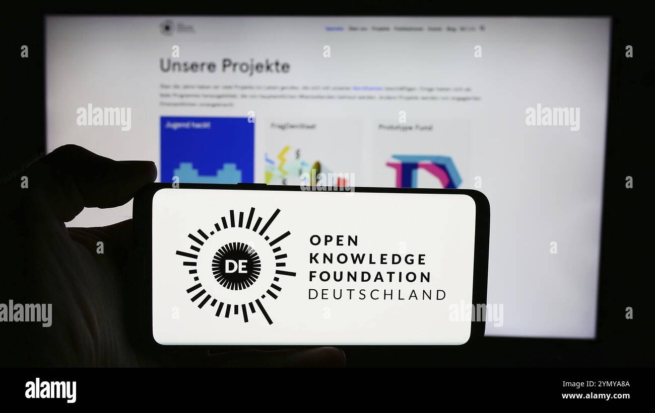 Stuttgart, 21.05.2024: Person mit Smartphone mit Logo der Open Knowledge Foundation Deutschland e.V. (OKFDE) vor der Website. Fokus o Stockfoto