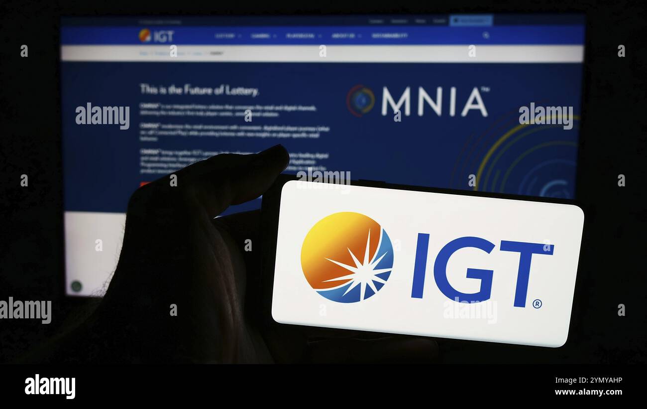 Stuttgart, Deutschland, 07.06.2024: Person, die ein Mobiltelefon mit dem Logo der Firma International Game Technology plc (IGT) vor der Business-Webseite hält Stockfoto