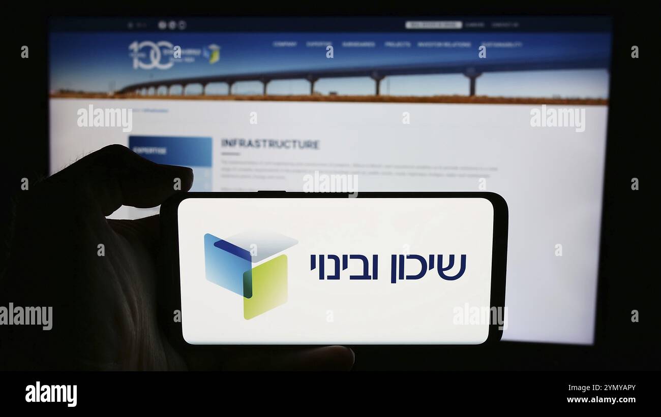 Stuttgart, 10.07.2024: Person, die ein Mobiltelefon mit dem Logo des israelischen Entwicklungsunternehmens Shikun und Binui vor der Webseite hält. Fokus Stockfoto