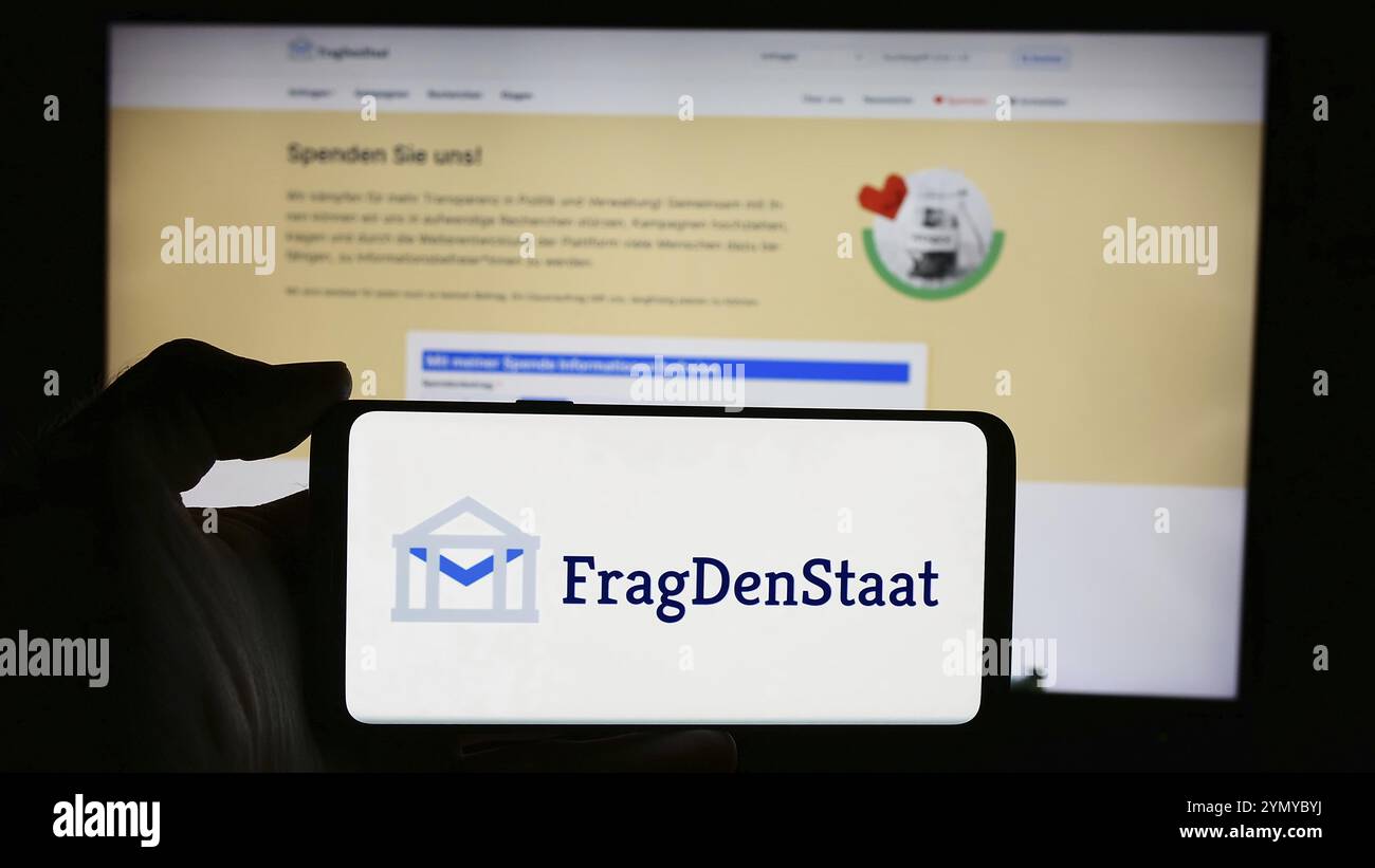 Stuttgart, 21.05.2024: Person mit Handy mit Logo der deutschen Nichtregierungsorganisation FragDenStaat vor der Webseite. Konzentrieren Sie sich auf Stockfoto
