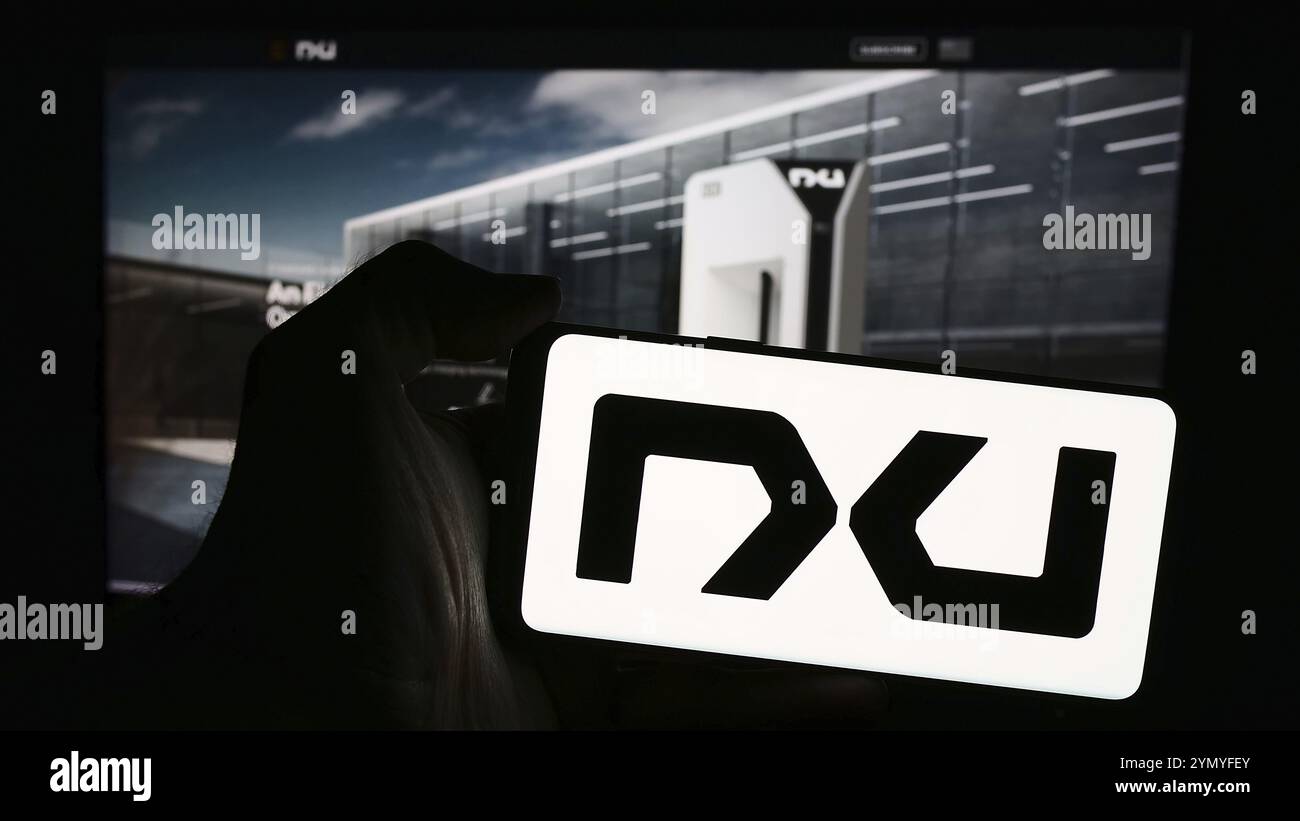 Stuttgart, Deutschland, 28.04.2024: Person, die ein Mobiltelefon mit Logo des amerikanischen Akkutechnologieunternehmens Nxu Inc. Vor der Business-Webseite hält. F Stockfoto
