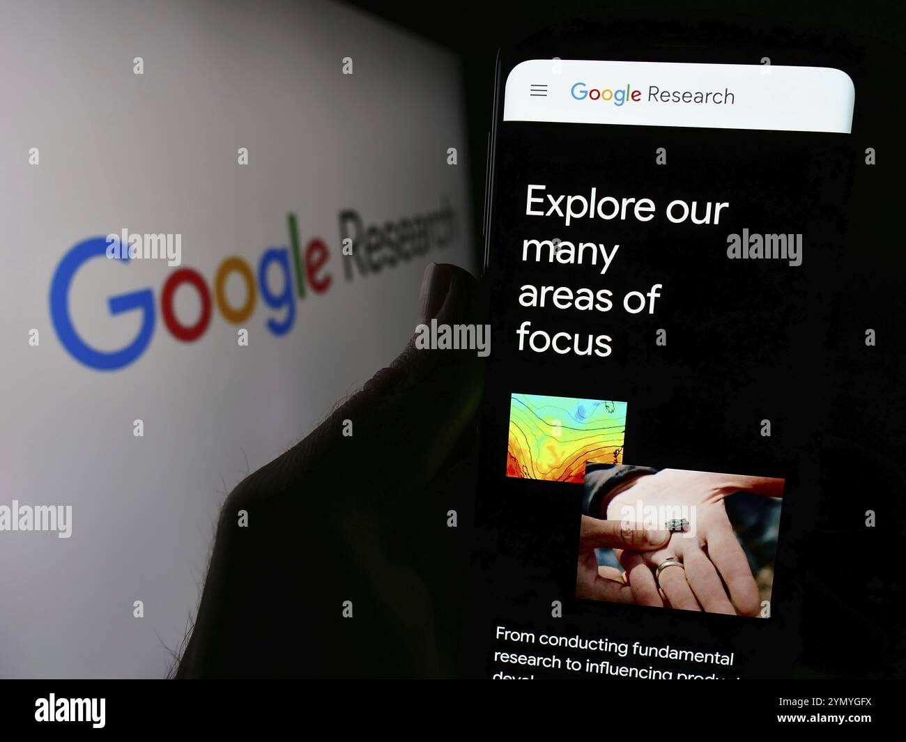 Stuttgart, Deutschland, 04.02.2024: Person, die ein Mobiltelefon hält, mit Webseite des US-Technologieunternehmens Google Research vor dem Firmenlogo. Schwerpunkt auf cen Stockfoto