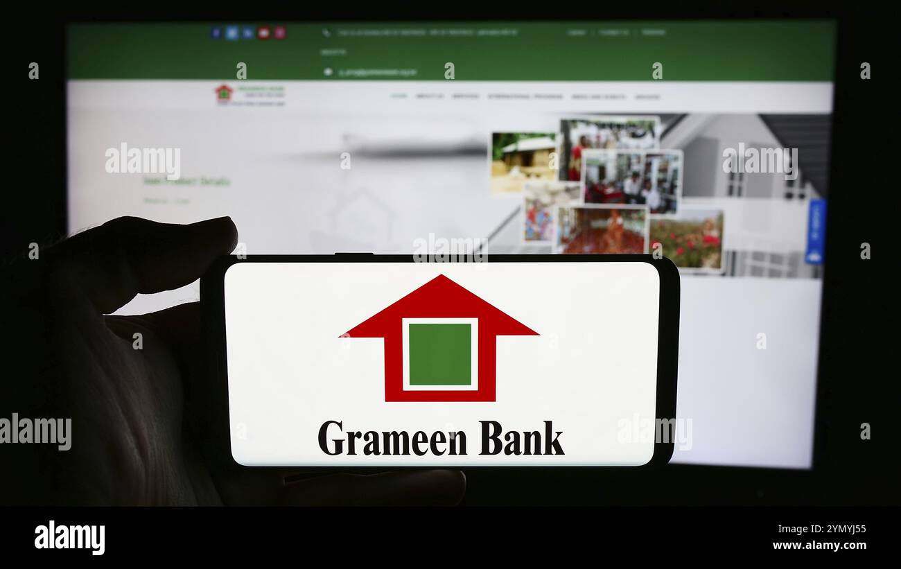Stuttgart, Deutschland, 06.07.2024: Person, die ein Mobiltelefon mit dem Logo des bangladeschischen Mikrofinanzunternehmens Grameen Bank vor der Business-Webseite hält. Fokussieren Stockfoto