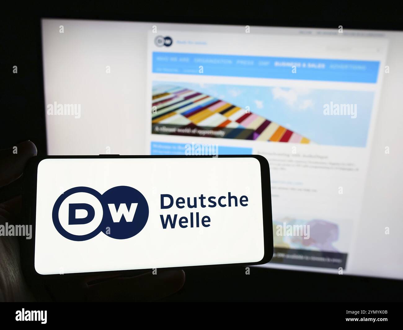 Stuttgart, Deutschland, 10.04.2024: Person mit Smartphone mit Logo der Deutschen Welle (DW) vor der Website. Fokus o Stockfoto