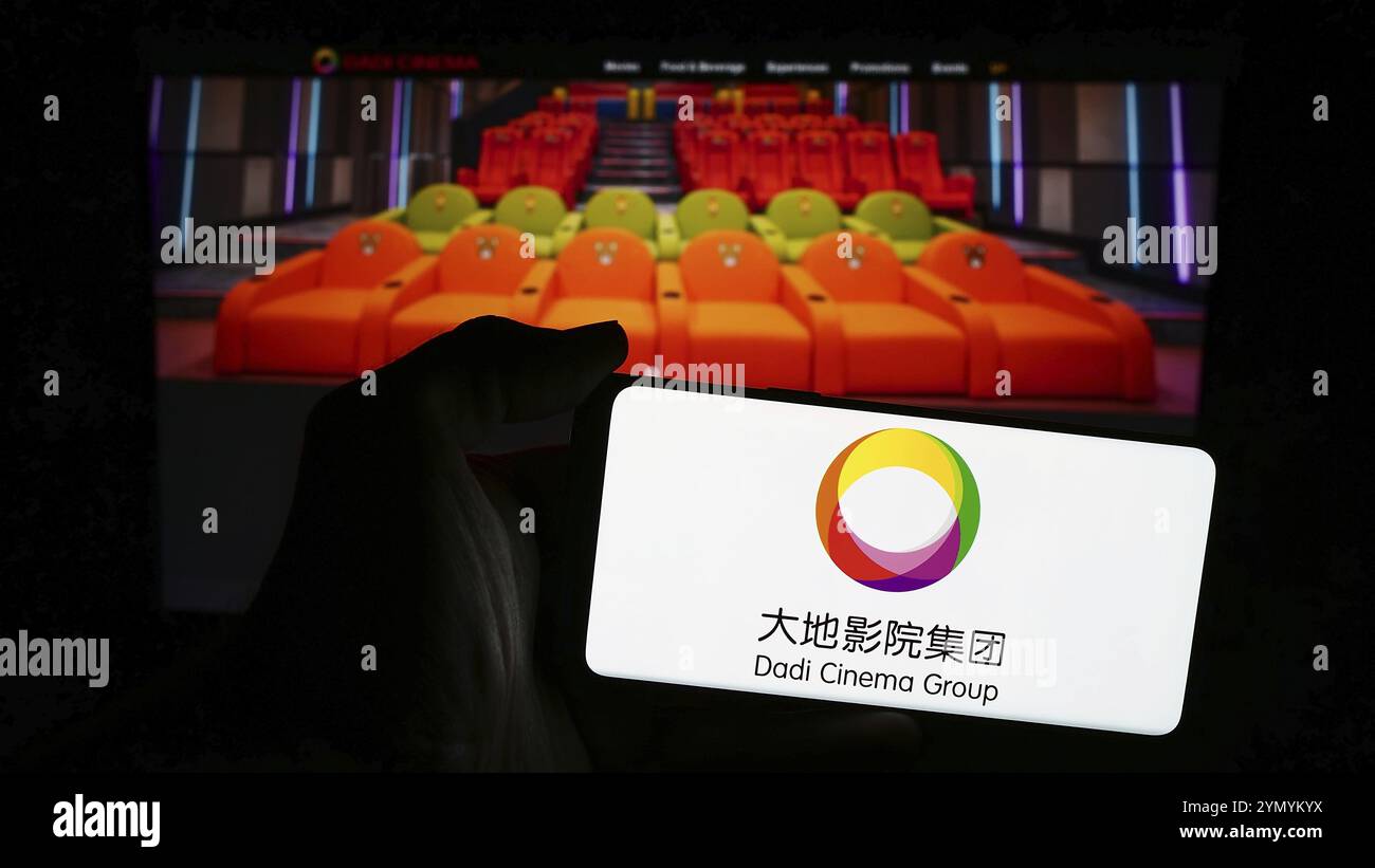 Stuttgart, Deutschland, 03.06.2024: Person, die ein Mobiltelefon mit dem Logo des asiatischen Unterhaltungsunternehmens Dadi Cinema vor der Business-Webseite hält. Fokus Stockfoto