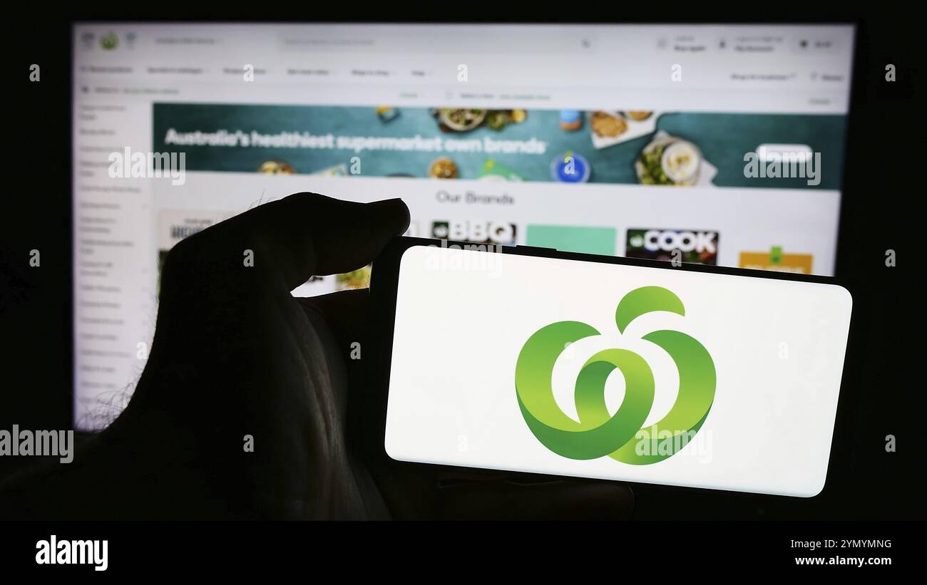 Stuttgart, 21.07.2024: Person mit Mobiltelefon mit Logo des australischen Einzelhandelskettenunternehmens Woolworths Supermarkets vor der Webseite. Stockfoto