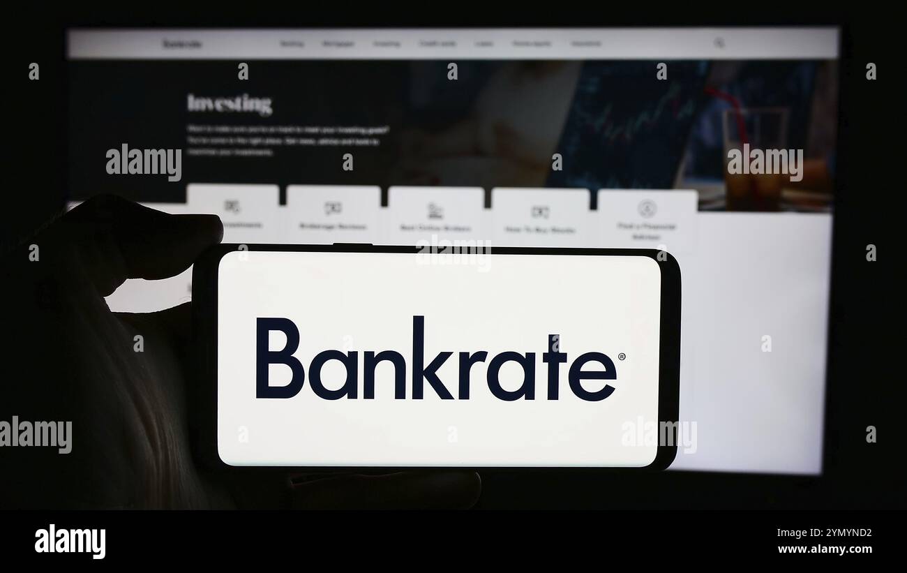 Stuttgart, Deutschland, 05.03.2024: Person mit Mobiltelefon mit Logo des US-amerikanischen Finanzunternehmens Bankrate LLC vor der Webseite. Konzentrieren Sie sich auf Stockfoto