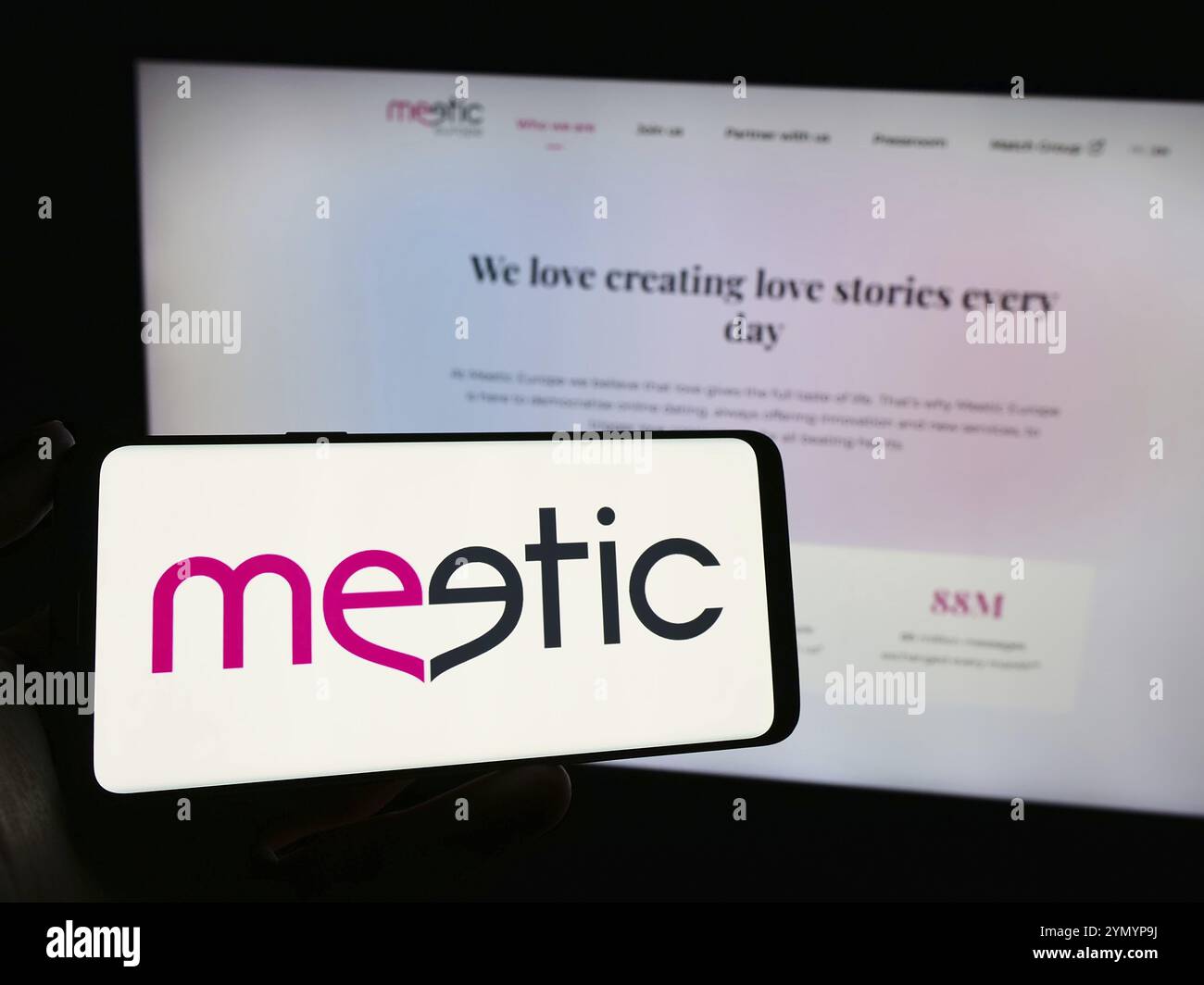 Stuttgart, Deutschland, 29.02.2024: Person mit Handy mit Logo der französischen Online-Dating-Firma Meetic SAS vor der Business-Webseite. Fokus Stockfoto