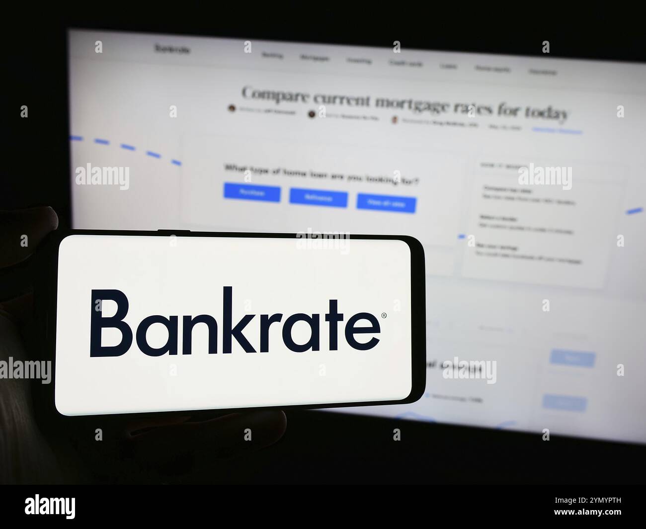 Stuttgart, Deutschland, 05-03-2024: Person, die ein Mobiltelefon mit dem Logo des amerikanischen Konsumentenfinanzierungsunternehmens Bankrate LLC vor der Webseite der Unternehmen hält. Stockfoto