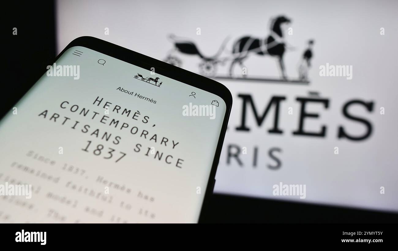 Stuttgart, 17.07.2024: Mobiltelefon mit Website des französischen Luxusunternehmens Hermes International S.A. vor dem Firmenlogo. Konzentrieren Sie sich auf Top-l Stockfoto