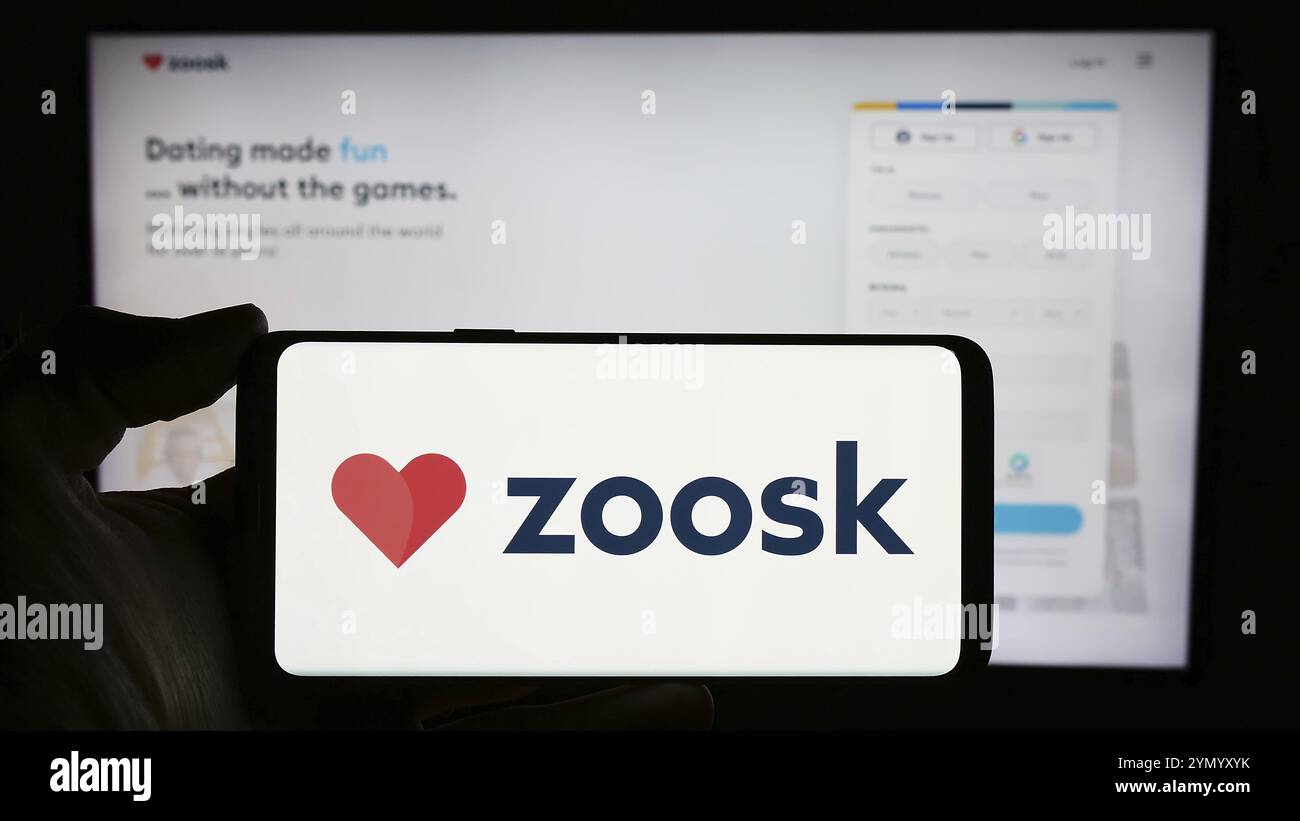 Stuttgart, Deutschland, 03-01-2024: Person mit Handy mit Logo der Online-Dating-Plattform-Firma Zoosk Inc. Vor der Business-Website. Konzentrieren Sie sich auf Stockfoto