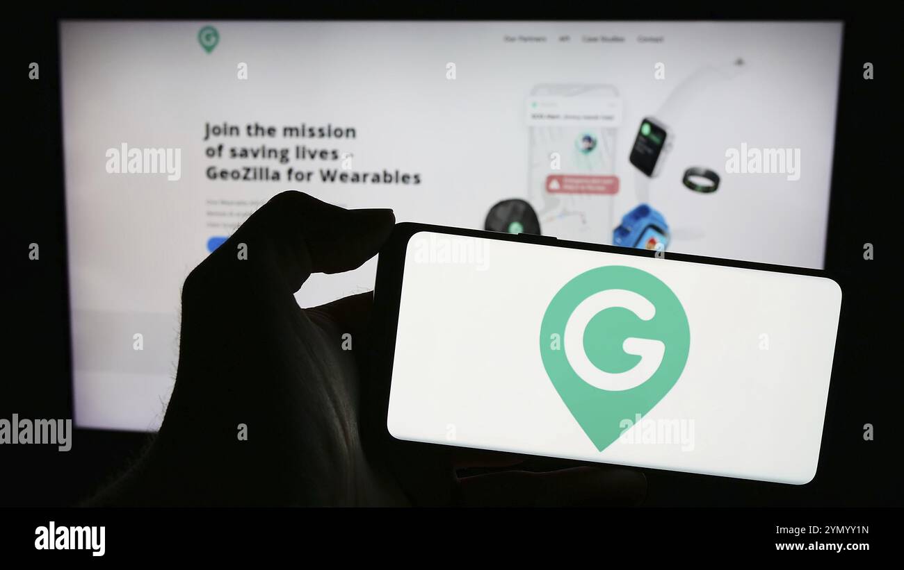 Stuttgart, 24.02.2024: Person, die ein Mobiltelefon mit dem Logo des amerikanischen GPS-Ortungsunternehmens GeoZilla Inc. Vor der Webseite hält. Fo Stockfoto