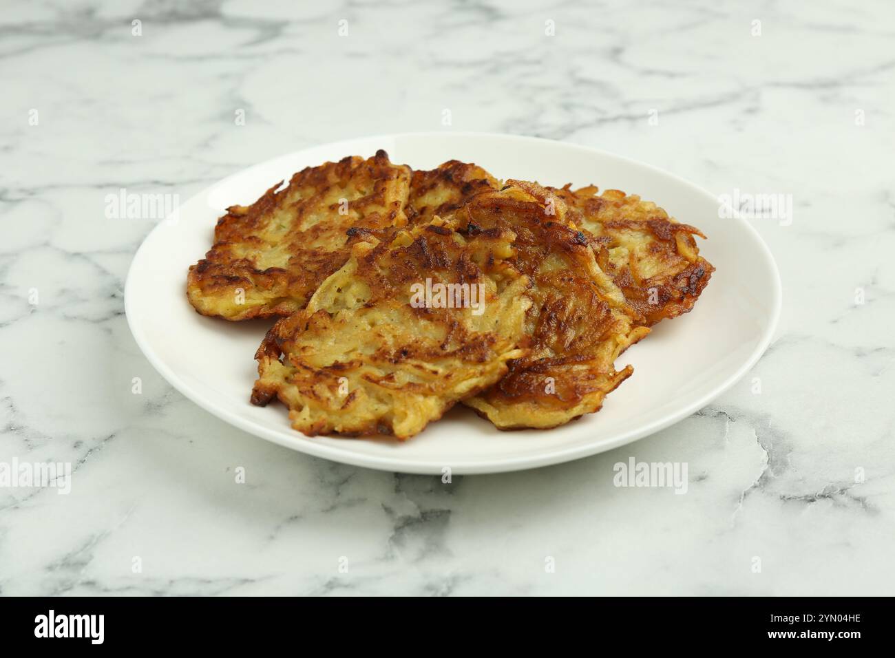 Leckere Kartoffelpfannkuchen auf weißem Marmortisch, Nahaufnahme Stockfoto
