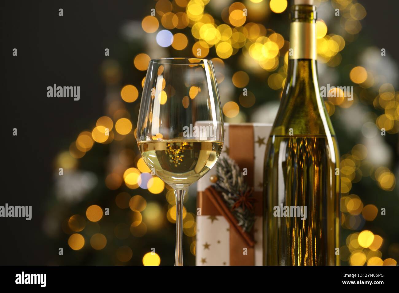 Wein im Glas, Flasche und Weihnachtsgeschenk gegen verschwommenes Licht, Nahaufnahme Stockfoto