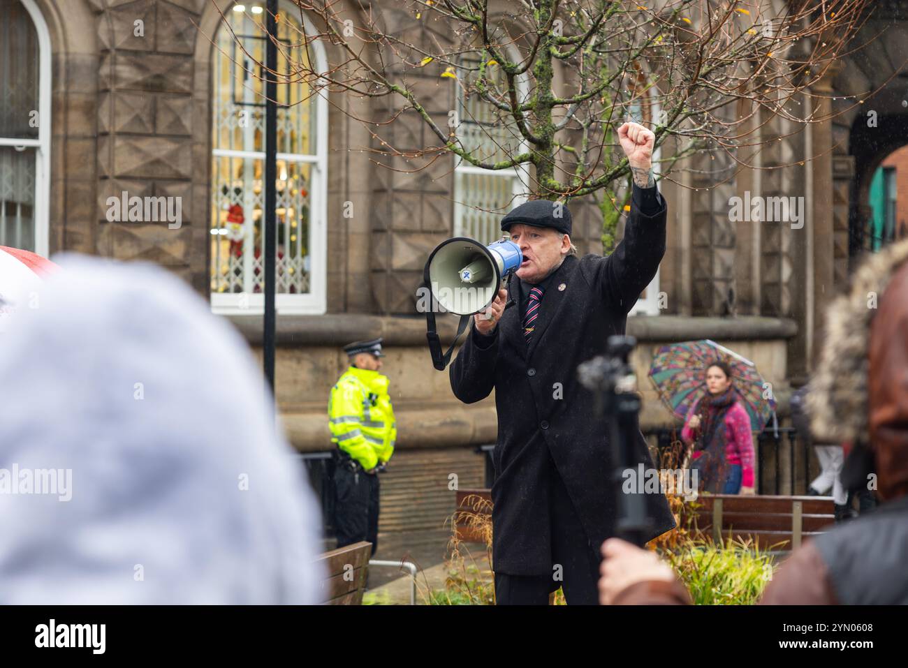 Leeds, Großbritannien. NOVEMBER 2024. Die Protestgruppen auf der rechten Seite erheben die Faust, als sich zwei rivalisierende Protestgruppen vor der Leeds Corn Exchange versammelten, während die widrigen Witterungsbedingungen durch Sturm Bert hervorgerufen wurden. Rechtsgerichtete Demonstranten, die vermutlich mit Hull Patriots / Hull Patriotic Protestistors verbunden sind, und andere rechtsseitige Organisationen hielten eine Demonstration mit etwa 25 Teilnehmern ab, ein Gegenprotest wurde von der linken Aktivistischen Gruppe SUTR (Stand Up to Rassismus) organisiert, die sich in kurzer Entfernung versammelte, die Polizei hielt die beiden Seiten bei starkem Regen getrennt. Quelle: Milo Chandl Stockfoto