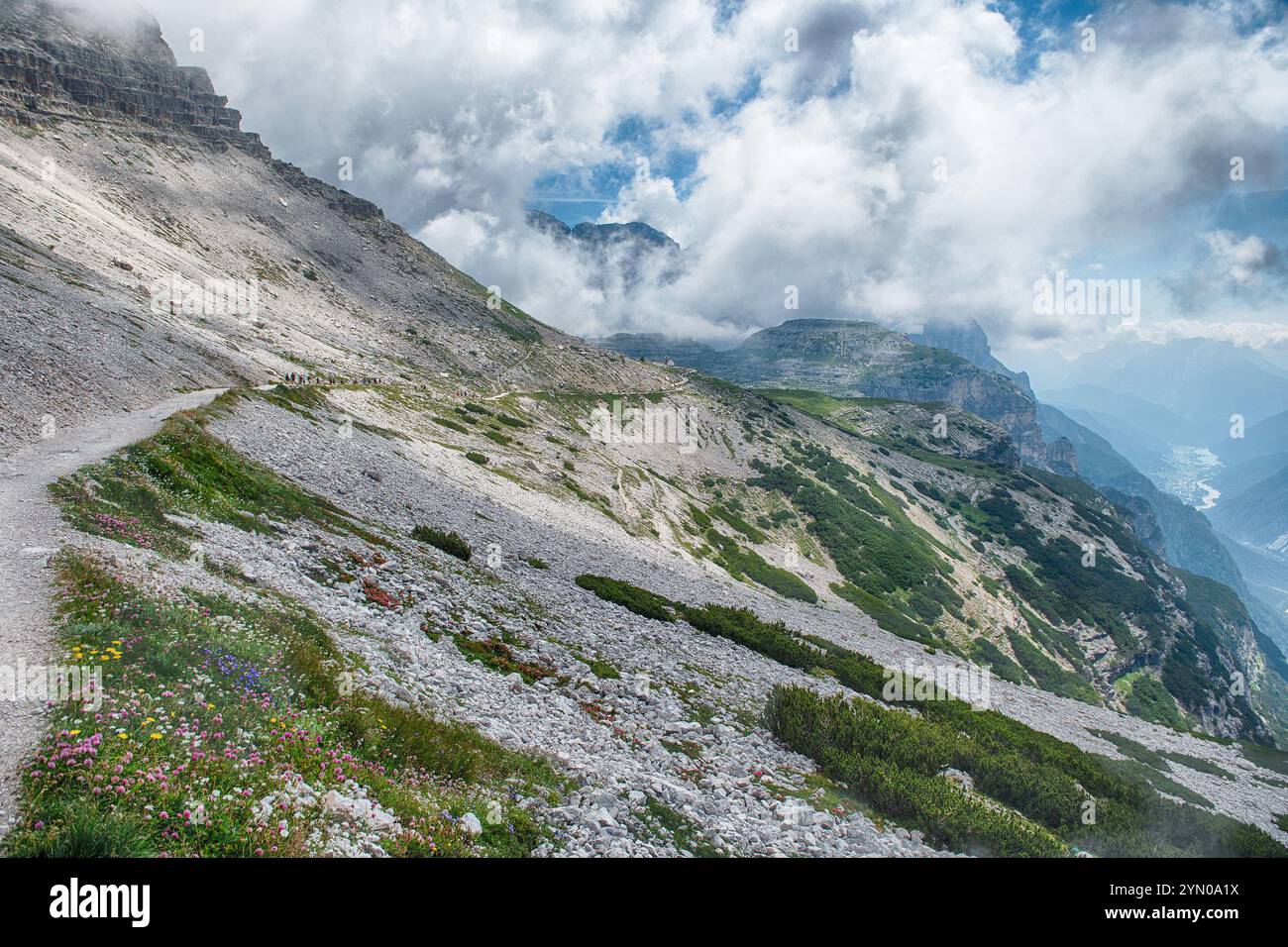 Wanderer, die auf einem felsigen Bergweg zu den berühmten Tre Cime di Lavaredo wandern, umgeben von Wolken in den italienischen alpen, Stockfoto