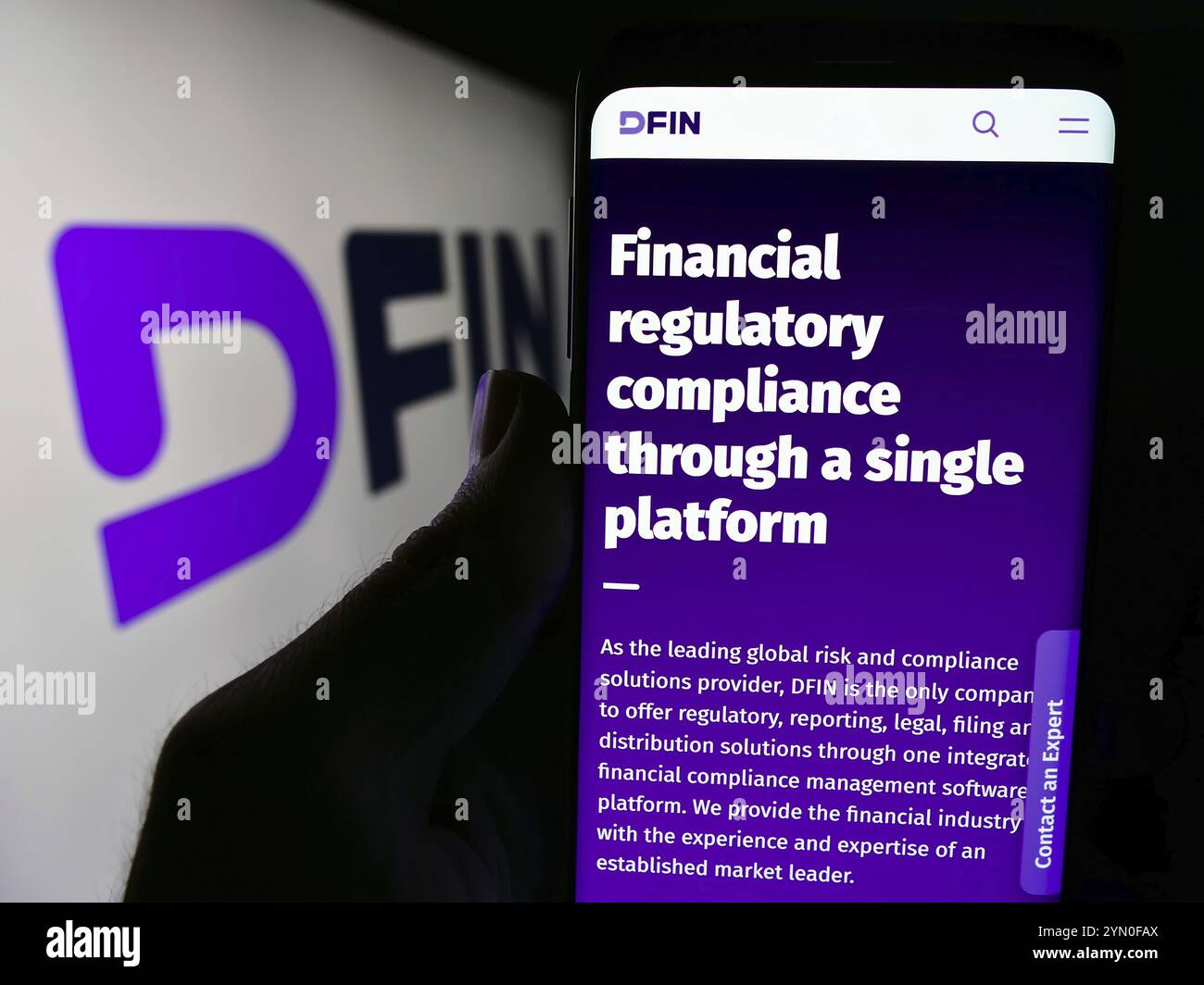 Stuttgart, Deutschland, 18.04.2024: Person, die ein Mobiltelefon hält, mit Webseite des US-amerikanischen Unternehmens Donnelley Financial Solutions Inc. (DFIN) vor dem Logo. Fokus Stockfoto
