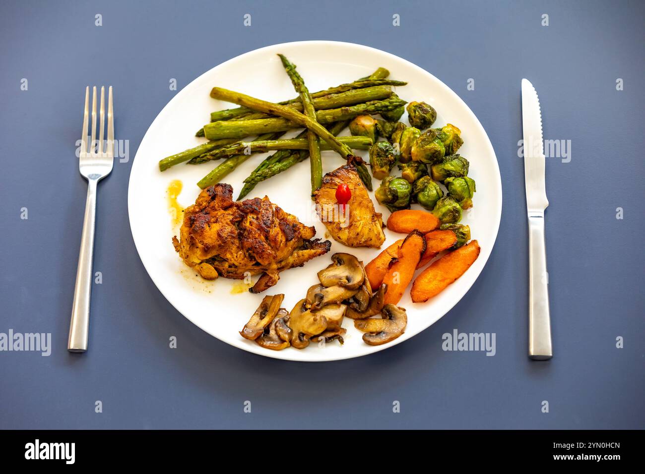 Echtes, starkes, gesundes, nahrhaftes Essen, gegrilltes Huhn, pimenta biquinho, Spargel, Pilze, Rosenkohl und Karotten. Stockfoto