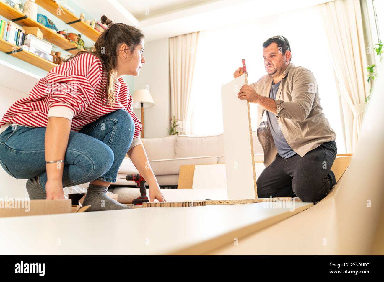 Ein junges Paar hat gerade geheiratet und ein Möbelstück in ihrem Haus montiert. Mit Schraubendreher und Werkzeugen in der Hand, um die Bedienungsanleitung zu befolgen. Handwerker c Stockfoto