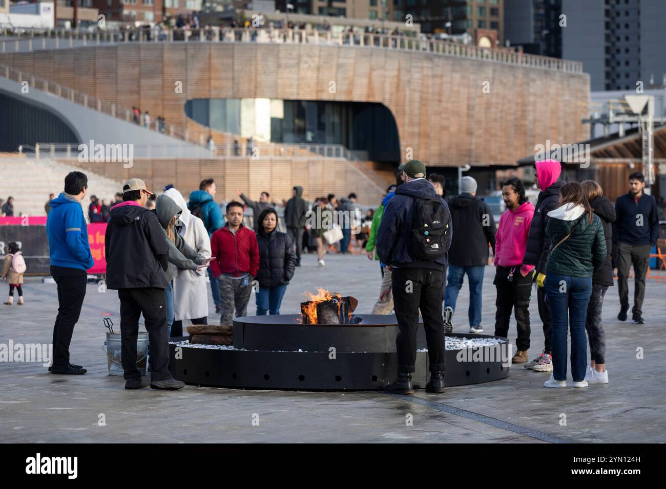 Am Samstag, 23. November 2024, wärmt sich der Besucher an einem Feuerring am Pier 62 entlang der Seattle Waterfront. Stockfoto