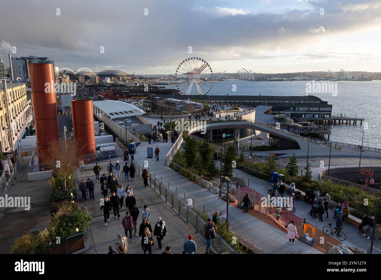 Am Samstag, den 23. November 2024, genießen Besucher den Sonnenuntergang entlang der Uferpromenade auf dem neuen Overlook Walk von Seattle. Stockfoto