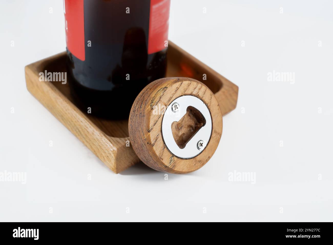 Kleiner handlicher, runder Flaschenöffner aus Holz mit Flaschenbecher, isoliert auf weißem Hintergrund Stockfoto