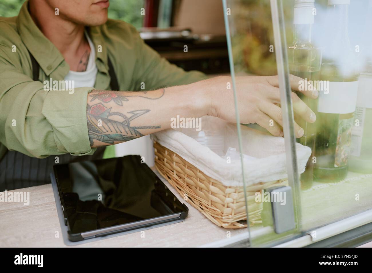Mittlere Nahaufnahme von tätowierten Händen, die Sirupe für Kaffee und Tee auf dem Tisch im Food Truck einstellen Stockfoto