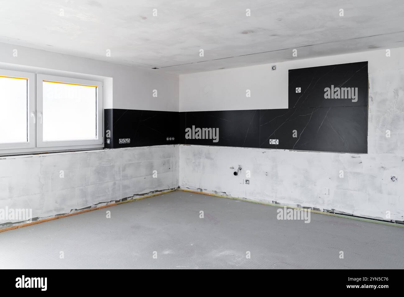 Moderne, unvollendete Kücheneinrichtung mit schwarzen Backsplash-Fliesen, installierten Steckdosen und Wänden für die Renovierung im zeitgenössischen Haus D vorbereitet Stockfoto