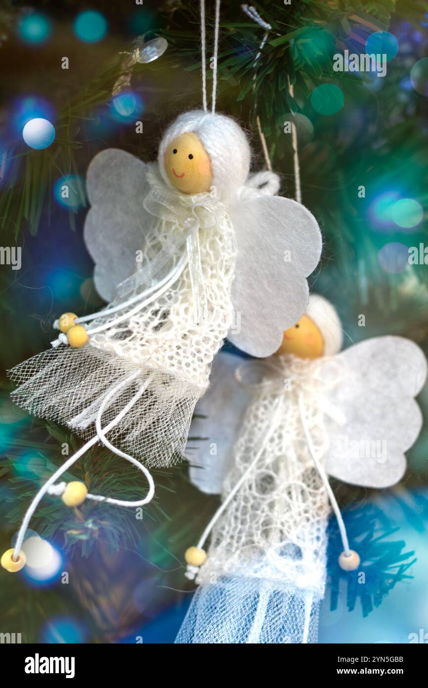 Zwei weiße, handgefertigte Engel schmücken den Weihnachtsbaum. Stockfoto