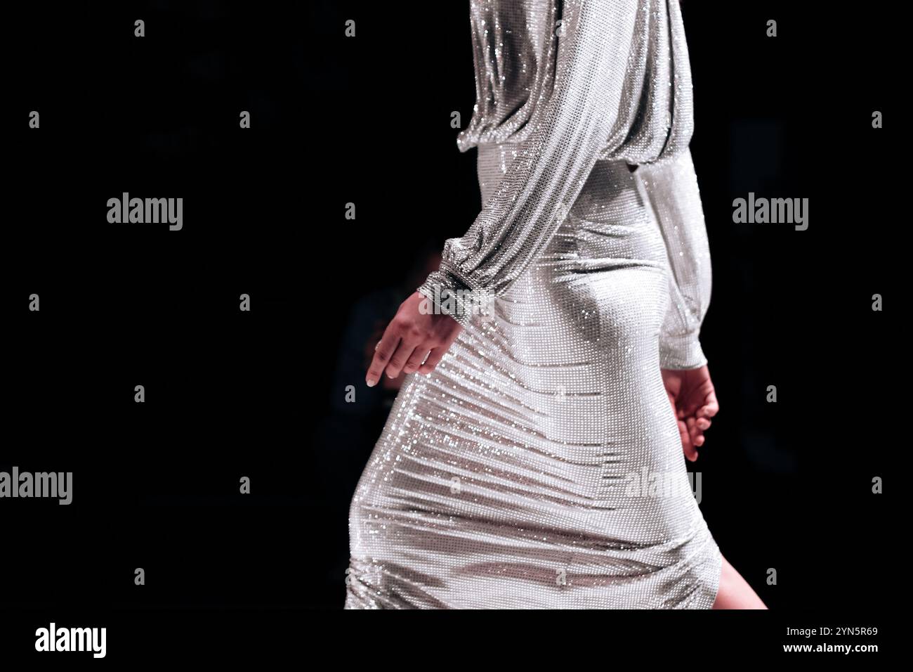 Nahaufnahme der Modedetails des silbernen weißen Kleides zur Feier des Feiertags, Models, das auf dem Laufsteg herumläuft Stockfoto