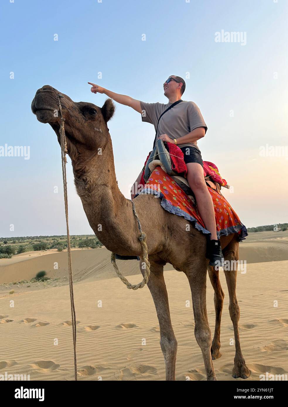 Touristen, die in die Ferne zeigen, während sie in der Wüste Thar in Rajasthan, Indien reiten Stockfoto