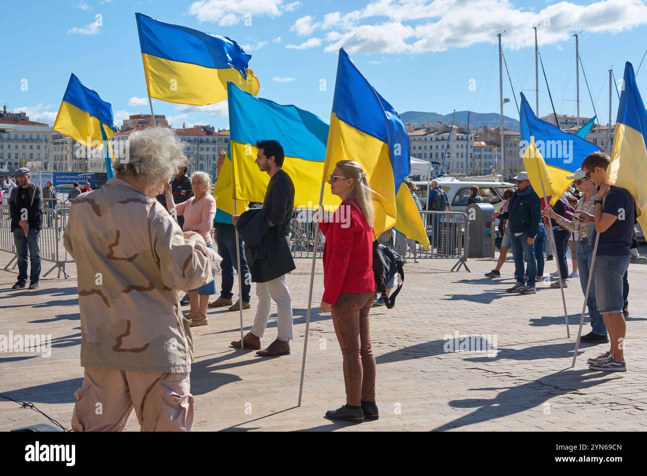 Marseille. Frankreich - 24. November 2024: Demonstration im Alten Hafen von Marseille, bei der Menschen unterschiedlichen Alters ukrainische Flaggen schwenken. Der blaue Himmel Stockfoto