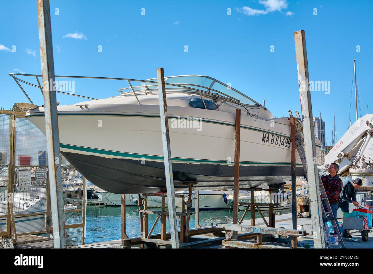 Marseille. Frankreich - 24. November 2024: Marina von Marseille, wo ein Boot namens Le Cap Cara auf einer Stütze stand und von zwei Personen instand gehalten wird. Stockfoto