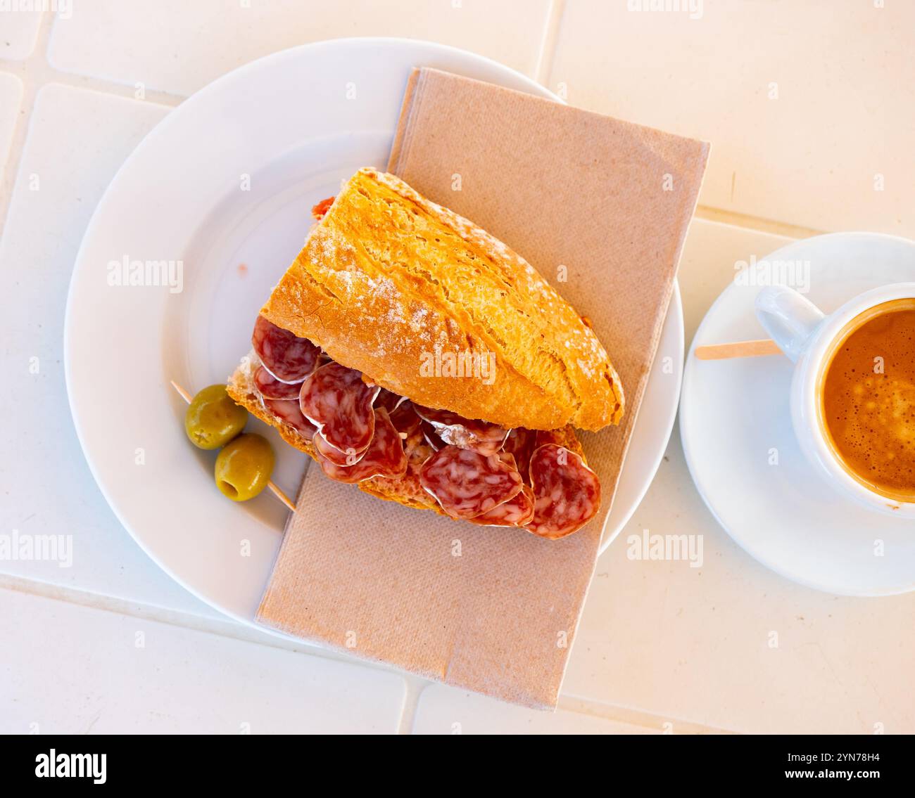 Spanisches Frühstück: Geräuchertes Würstchen-Fuet-Sandwich und Oliven in der Nähe Stockfoto