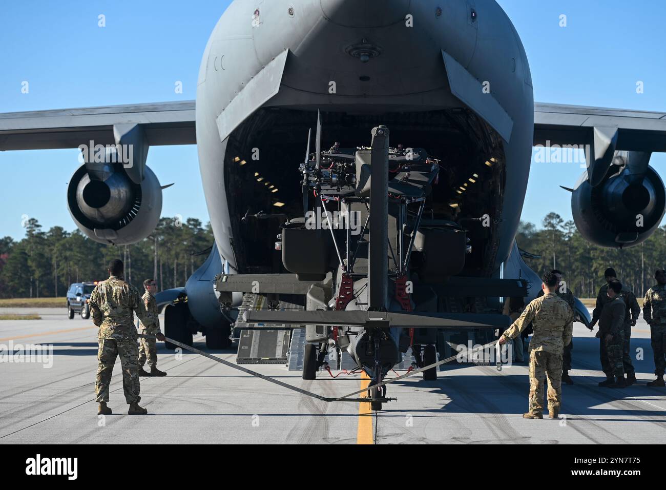 Am 21. November 2024 bereiten sich Mitarbeiter der US-Armee darauf vor, Einen Hubschrauber der Boeing AH-64 Apache in ein Transportflugzeug der US Air Force C-17 Globemaster III auf der McEntire Joint National Guard Base in South Carolina zu laden. Die South Carolina National Guard führt in Zusammenarbeit mit dem 315th Airlift Wing eine Luftfahrtzertifizierung durch, um ein neu entwickeltes Blattfaltset für den AH-64 Apache Hubschrauber zu testen. Das Klingenklapppaket, das entwickelt wurde, um die Betriebseffizienz zu verbessern, ist 100 kg leichter als sein Vorgänger und stellt damit einen bedeutenden Fortschritt in der Luftfahrttechnik und Mobilität dar. Das Feuerzeugmesser f Stockfoto