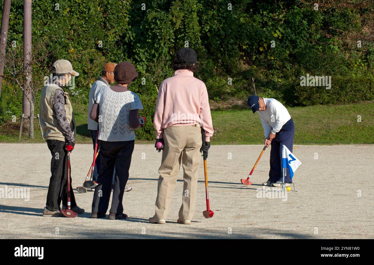 Gruppe japanischer Senioren, die an einem sonnigen Nachmittag in Hikone, Präfektur Shiga, Japan, Gateball (Krocket) spielen. Stockfoto