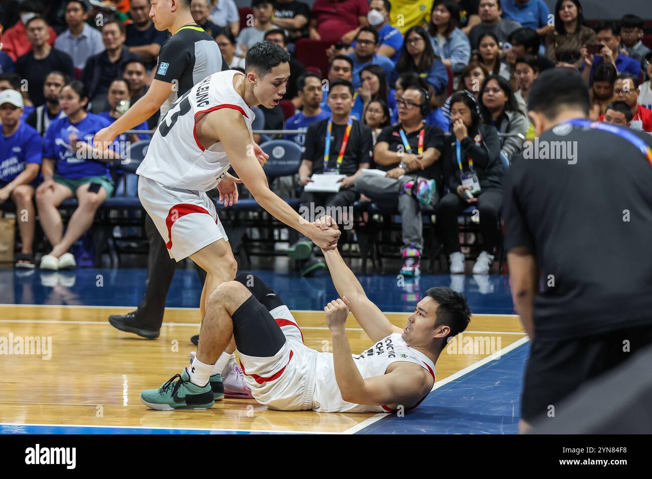 Pasay City, Philippinen. November 2024. Ka hin Marco Leung (L) aus Hongkong hilft seinem Teamkollegen Choi Kwan Tsai, während des Spiels zwischen den Philippinen und Hongkong beim FIBA Asia Cup 2025 Qualifying in Pasay City, Philippinen, am 24. November 2024 aufzustehen. Quelle: Rouelle Umali/Xinhua/Alamy Live News Stockfoto