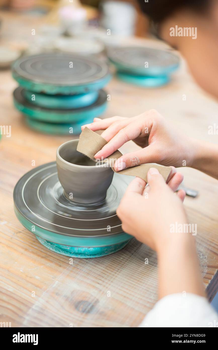 Frauenhände drehen das Töpferrad bei einem Töpferkurs Stockfoto