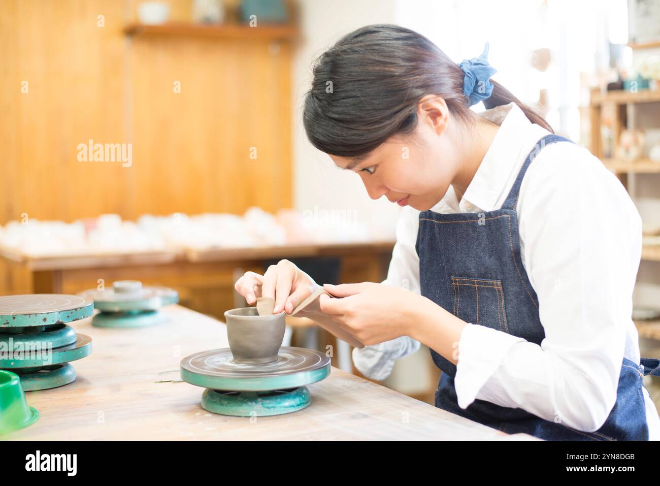 Frau, die ein Töpferrad in einem Töpferkurs dreht Stockfoto