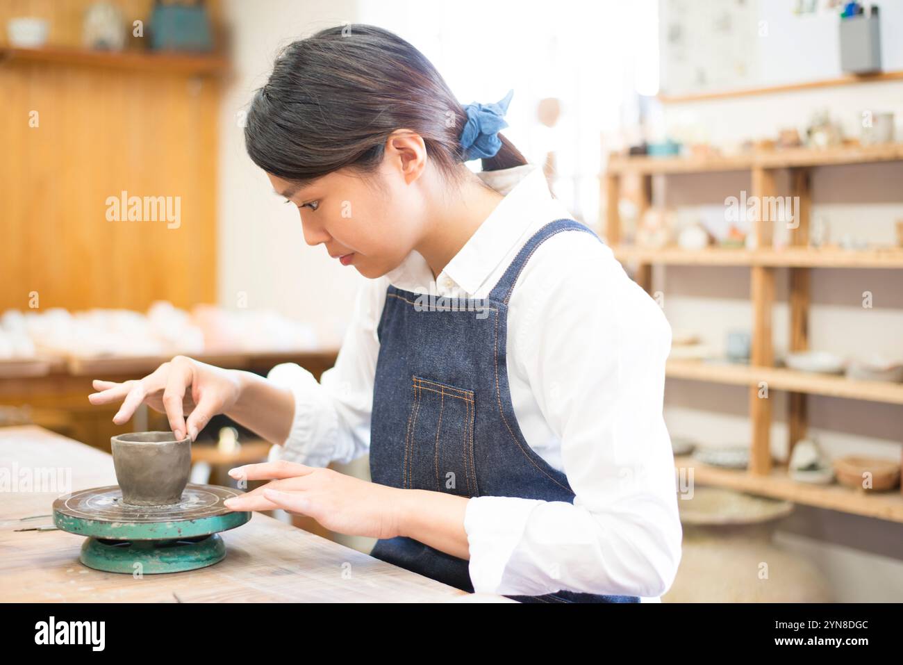 Frau, die ein Töpferrad in einem Töpferkurs dreht Stockfoto