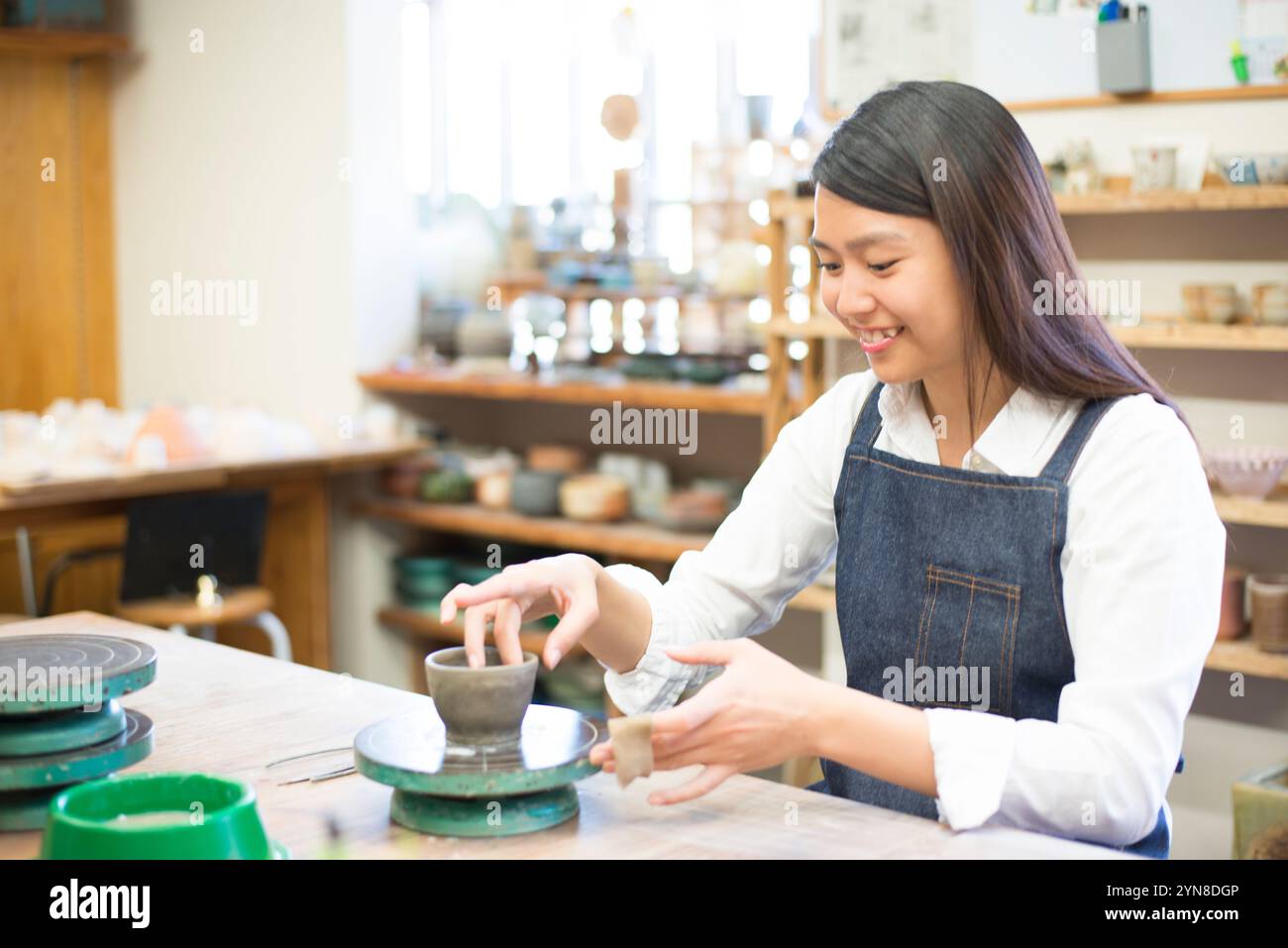 Frau, die ein Töpferrad in einem Töpferkurs dreht Stockfoto