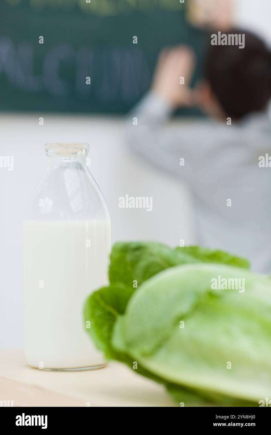 Kind an der Tafel mit Milch und Gemüse Stockfoto