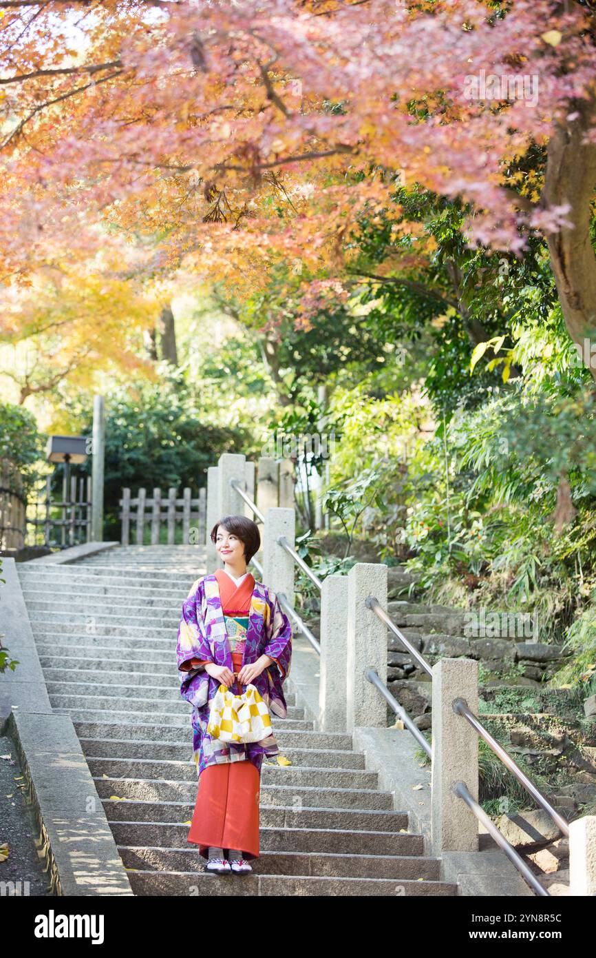 Frau in ihren 30ern, die einen Kimono trägt und die Herbstblätter genießt. Stockfoto
