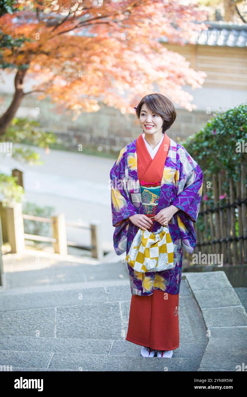 Frau in ihren 30ern, die einen Kimono trägt und die Herbstblätter genießt. Stockfoto