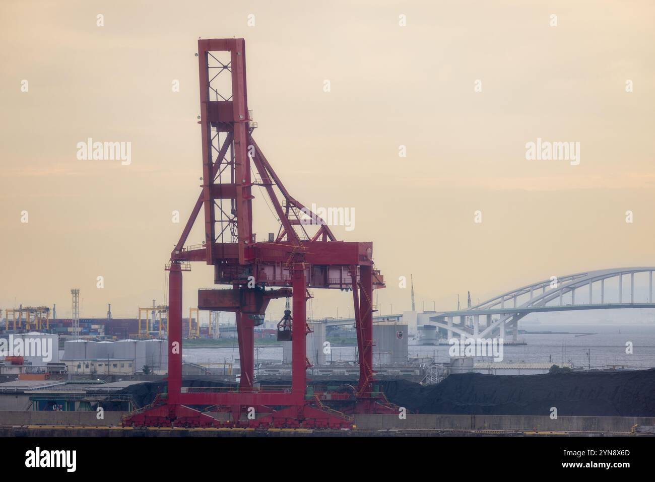 Roter Kran mit Brücke und Schiffshafen im Hintergrund Stockfoto