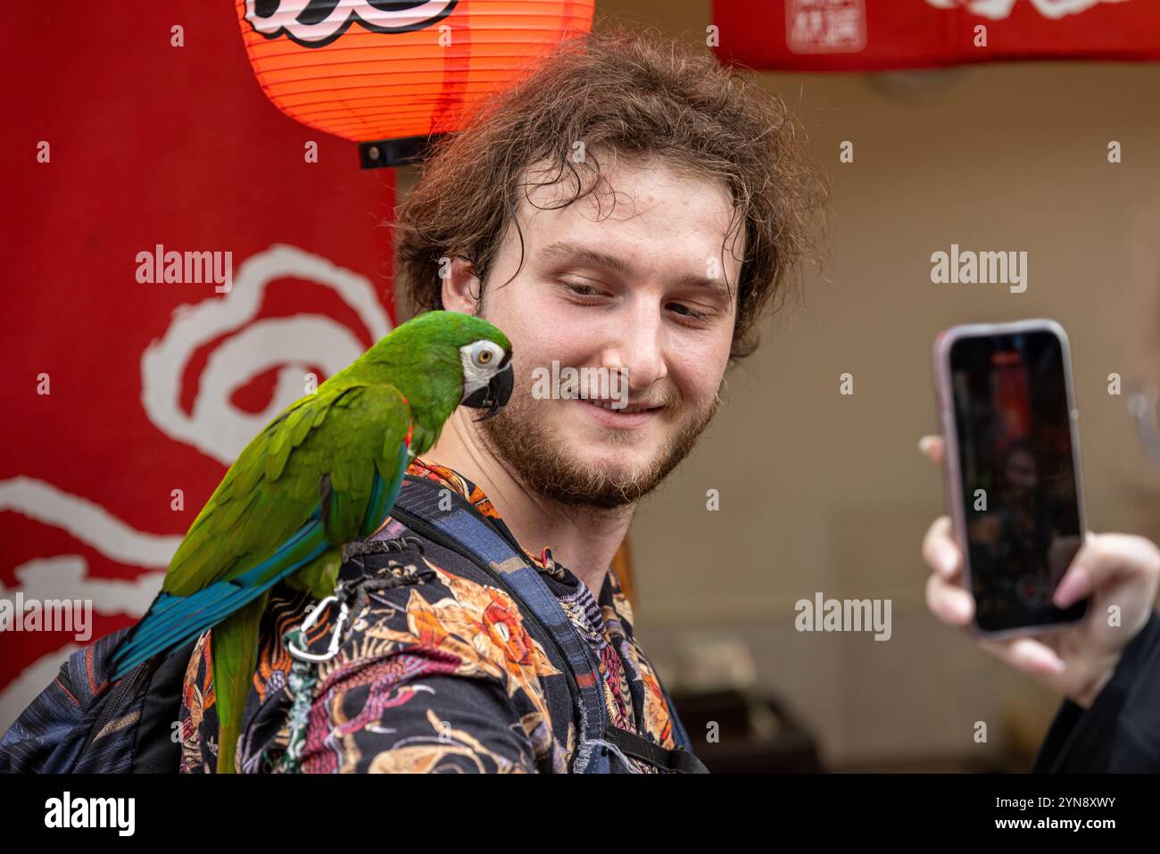 Mann, der sich mit tropischem Papagei vor einem bunten Hintergrund einlässt Stockfoto