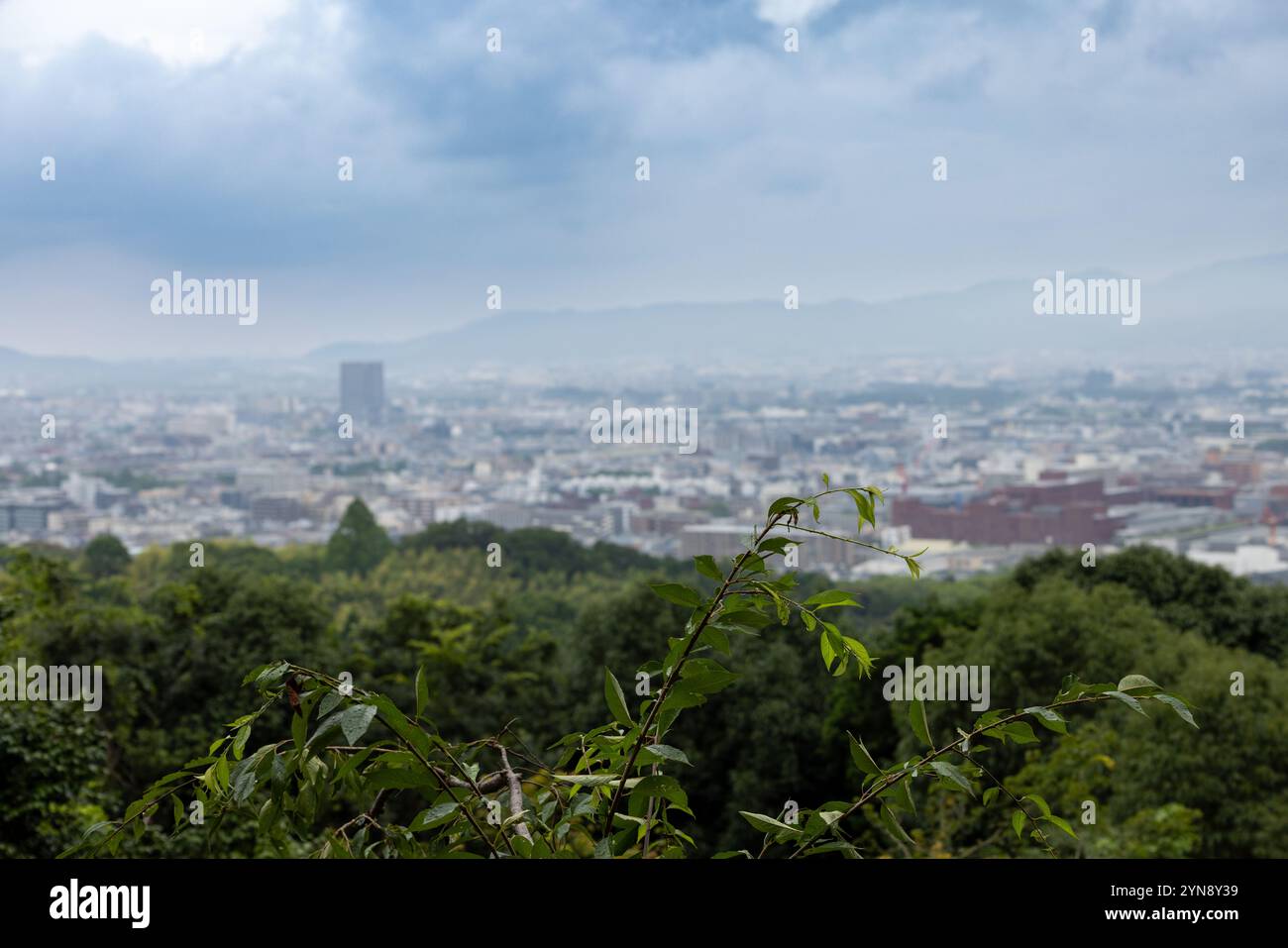 Kyoto Stadtbild umrahmt von Grün unter einem bewölkten Himmel Stockfoto