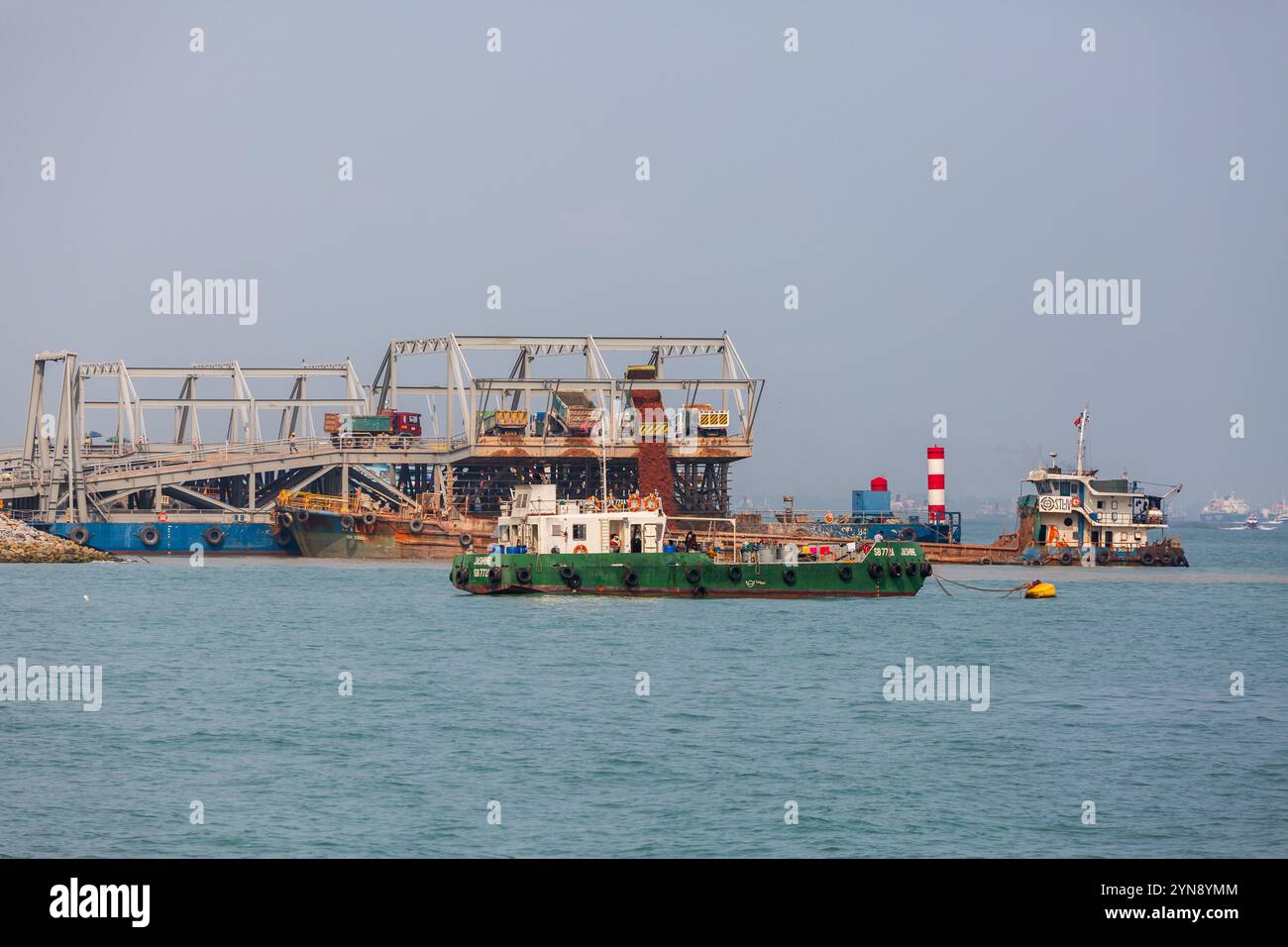 Sandwagen gießen Sand in das Meer für die Landgewinnung. Industriearbeiten in Marina Bay. Singapur Stockfoto