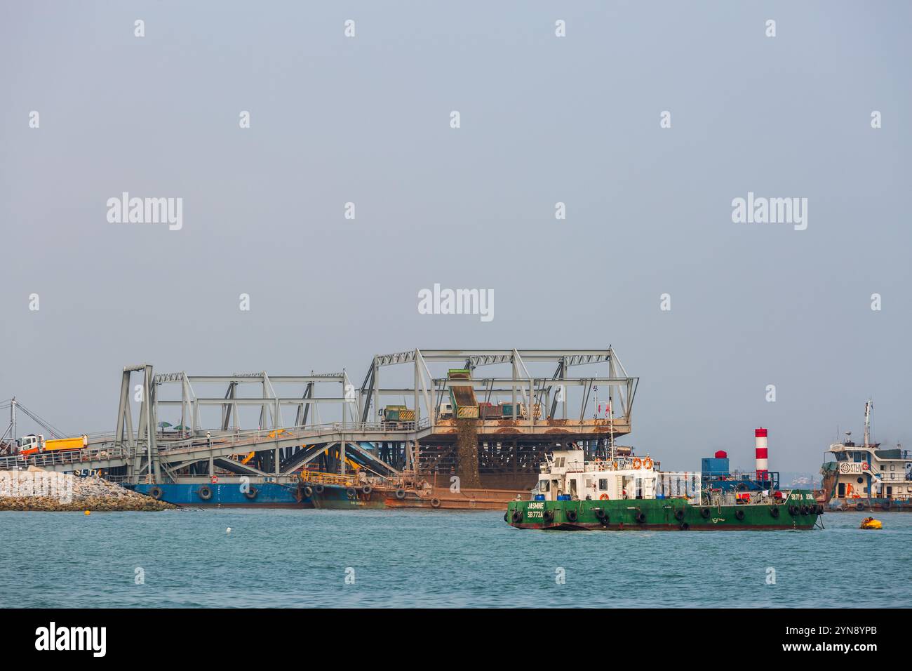 Sandwagen gießen Sand in das Meer für die Landgewinnung. Industriearbeiten in Marina Bay. Singapur Stockfoto